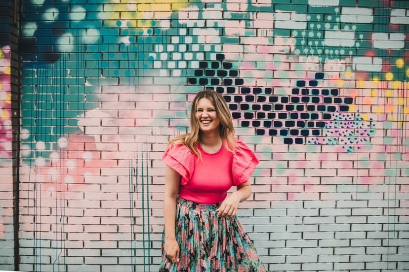 a female standing infront of a colourful wall